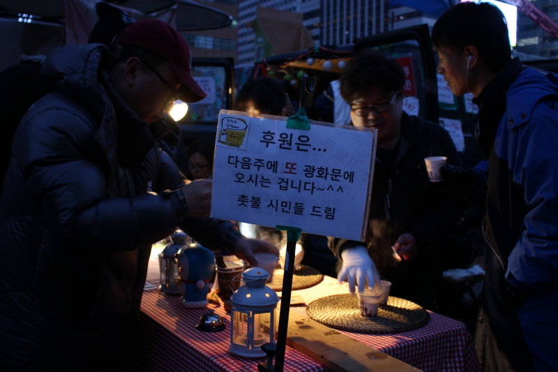 ▲ 박근혜 정권 퇴진 비상국민행동이 주관하는 제16차 촛불집회가 열린 18일 오후 광화문 광장에서 열렸다. 자원봉사자들이 시민들에게 무료 코코아를 나눠주고 있는 모습. 사진=김도연 기자