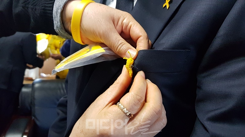 ▲ 13일 세월호 유가족이 MBC 신임 이사진의 옷깃에 손수 만든 노란 리본을 달아주고 있다.  사진=노지민 기자