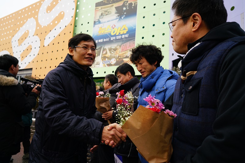 ▲ 유진영 언론노조 OBS지부장(왼쪽)이 18일 해직자들에게 꽃다발을 건네며 맞이하고 있다. 사진=OBS지부