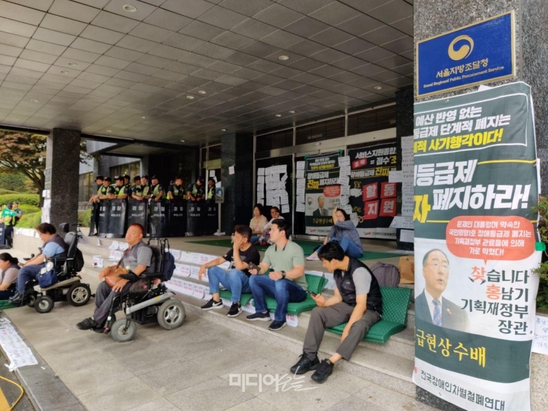 ▲28일 오전 전장연 활동가들이 경찰이 서울지방조달청 입구를 막아선 가운데 농성을 이어가고 있다. 사진=김예리 기자