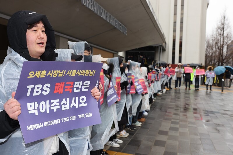 ▲ 21일 오전 TBS 구성원과 가족들이 서울시의회 앞에서 폐국을 막아달라는 손팻말을 들고 있다. 사진=TBS 두 노조 제공