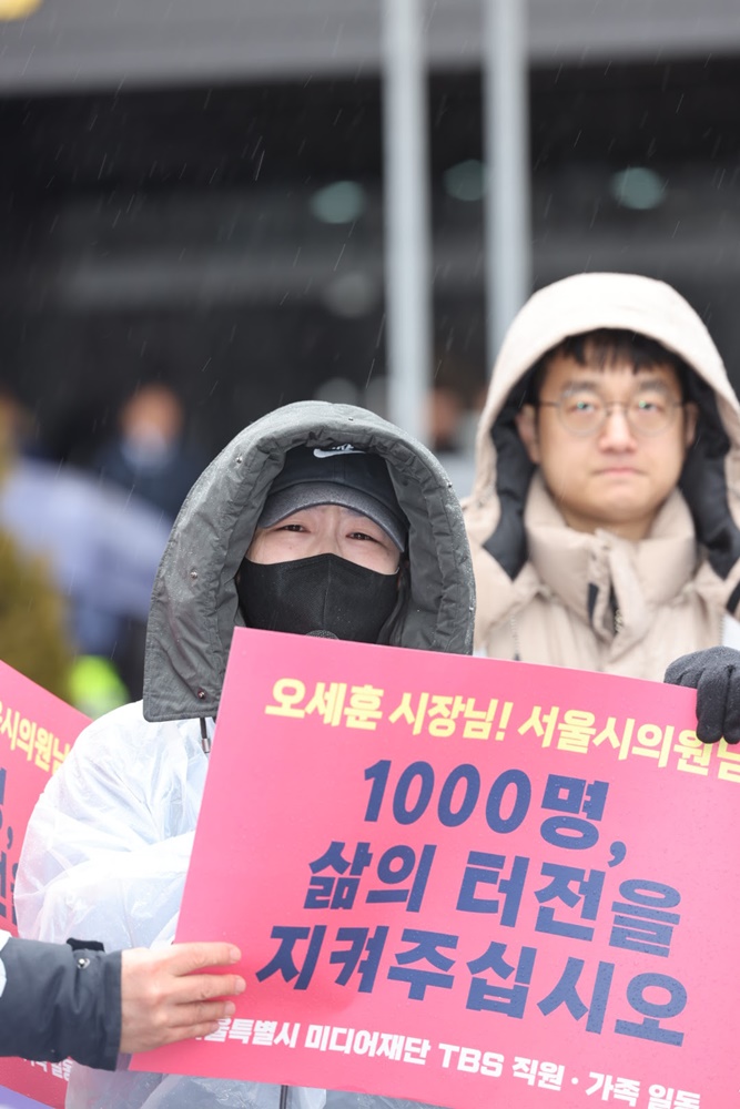 ▲ 21일 오전 TBS 구성원과 가족들이 서울시의회 앞에서 폐국을 막아달라는 손팻말을 들고 있다. 사진=TBS 두 노조 제공