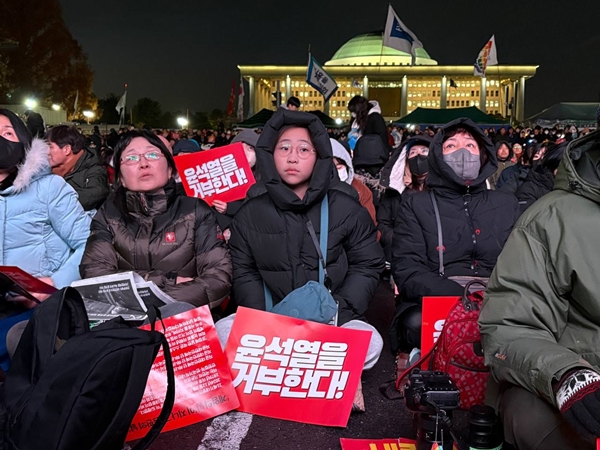 ▲ 7일 오후 국민의힘 의원들이 윤석열 대통령 탄핵소추안 표결을 앞두고 집단으로 국회 본회의장을 빠져나간 후 국회 앞 국회대로에서 생중계로 이를 지켜보던 시민들의 한숨섞인 한탄과 분노가 쏟아졌다. 한참동안 멍하니 생중계 화면을 바라보는 시민들도 있었다. 사진=윤유경 기자.